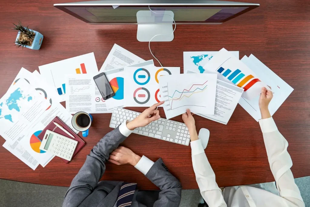 Réunion autour de graphiques et cartes, deux personnes analysent des données de vente et de performance client