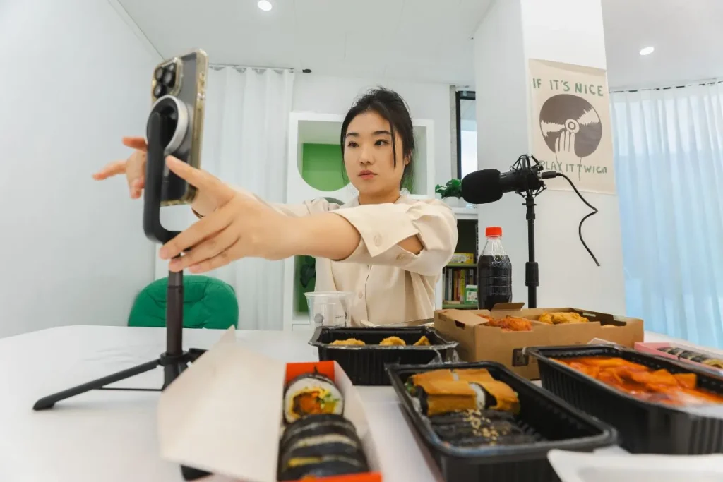 Créateur de contenu ajustant son smartphone devant des plats, image d’une stratégie pour monétiser son blog