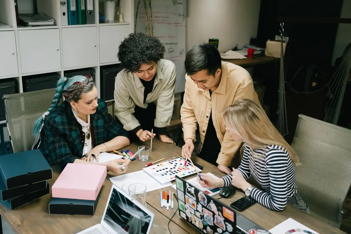 Quatre personnes autour d’une table analysent des visuels et couleurs illustrant une séance de brainstorming créatif dédiée au buzz marketing.