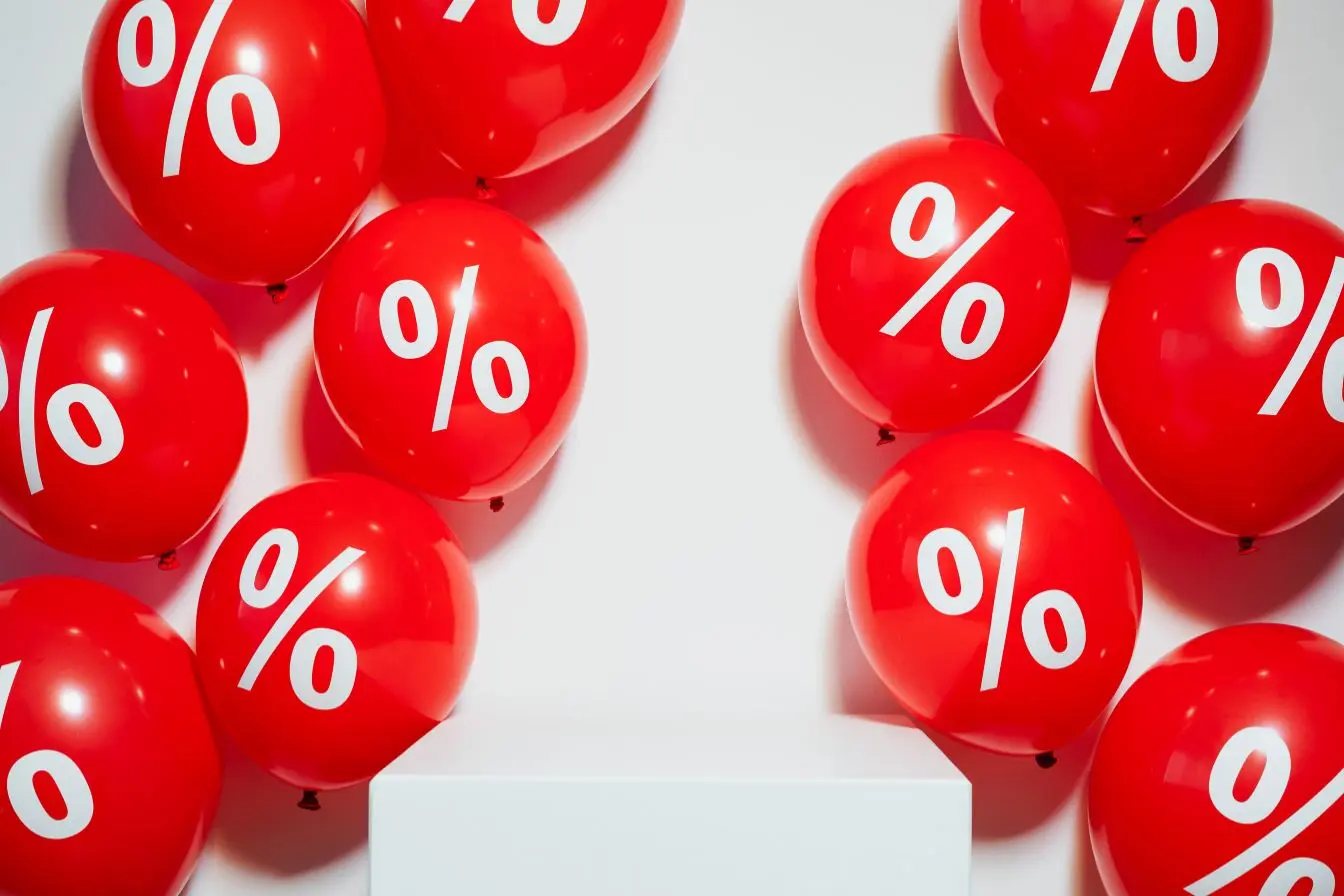 Ballons rouges avec symbole pourcentage autour d’un socle blanc, image illustrant le churn rate et la perte de clients dans un contexte marketing.