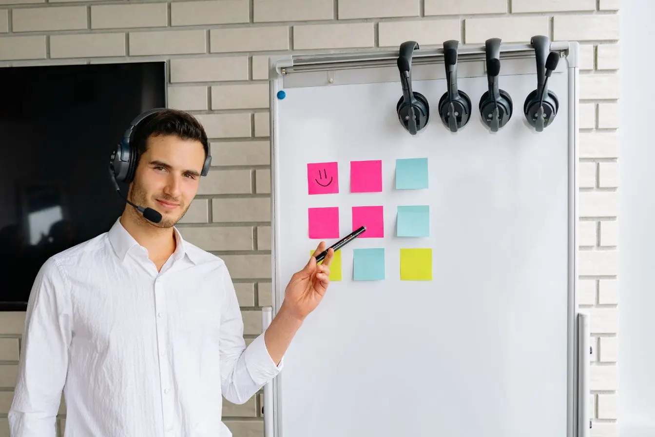 Personne en chemise blanche anime un tableau de post‑its colorés, illustrant la collaboration et la stratégie de co‑marketing entre partenaires.