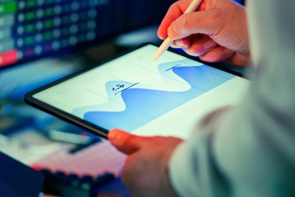 Personne utilisant stylet sur tablette affichant courbes bleues, image illustrant l’analyse de données rendue possible par le Machine Learning.