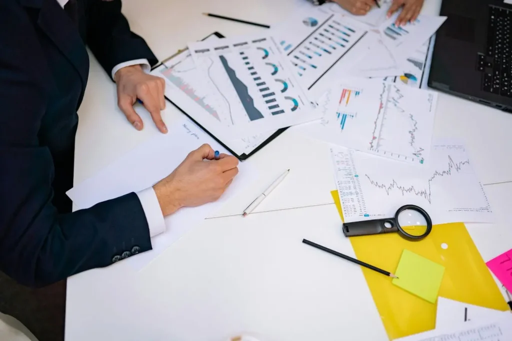 Deux personnes en costume analysent graphiques financiers, image illustrant la Due Diligence et l’examen rigoureux des données pour sécuriser décisions.