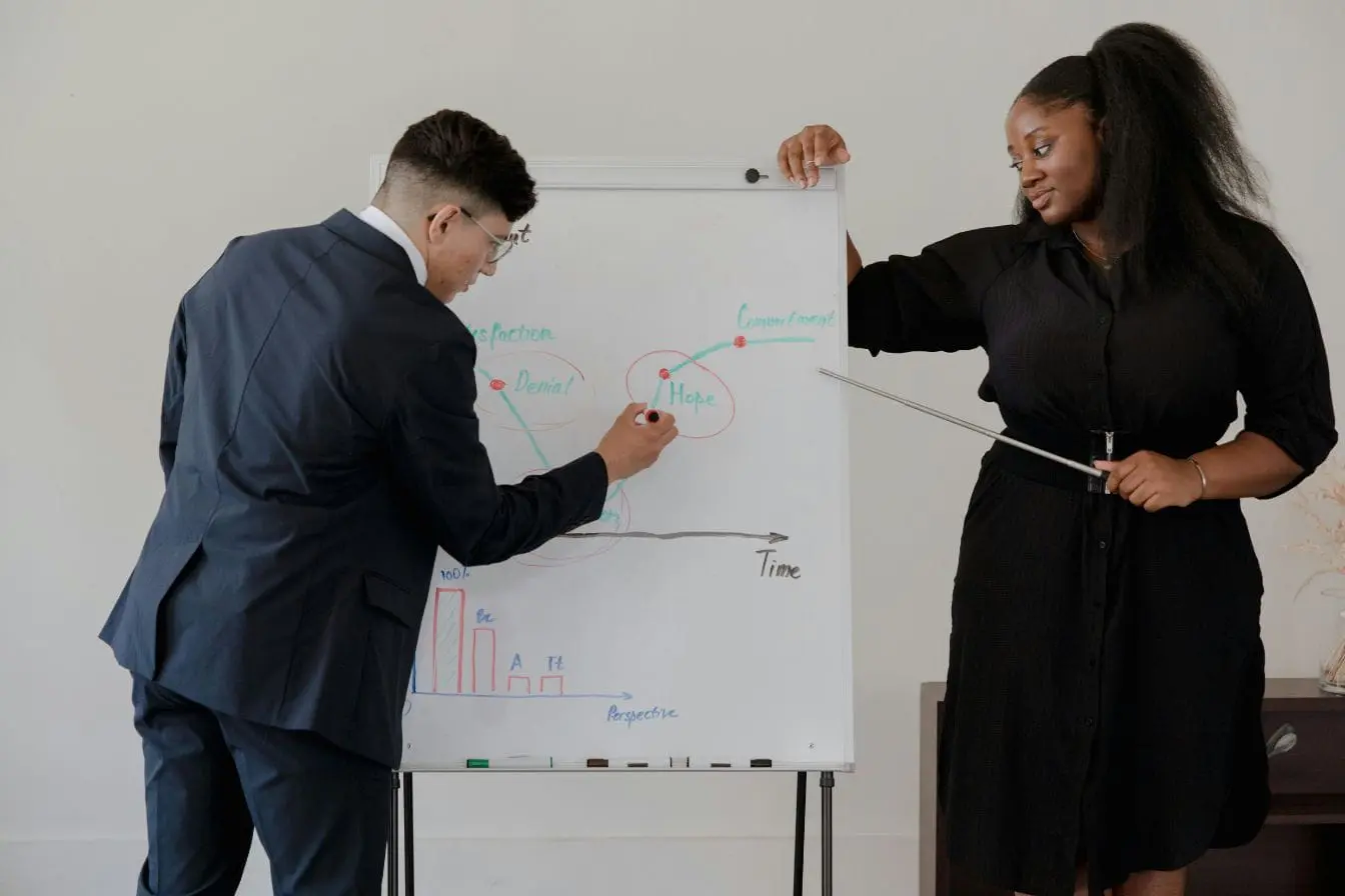 Due Diligence Deux personnes devant tableau blanc, image illustrant une analyse de données et la pratique de la Due Diligence en contexte professionnel.