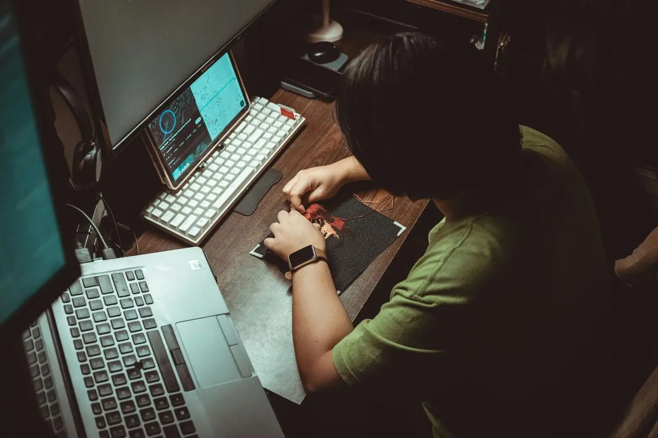 Bureau organisé mêlant couture manuelle et écrans numériques montrant graphiques, symbole d’un travail hybride soutenu par le cloud computing.