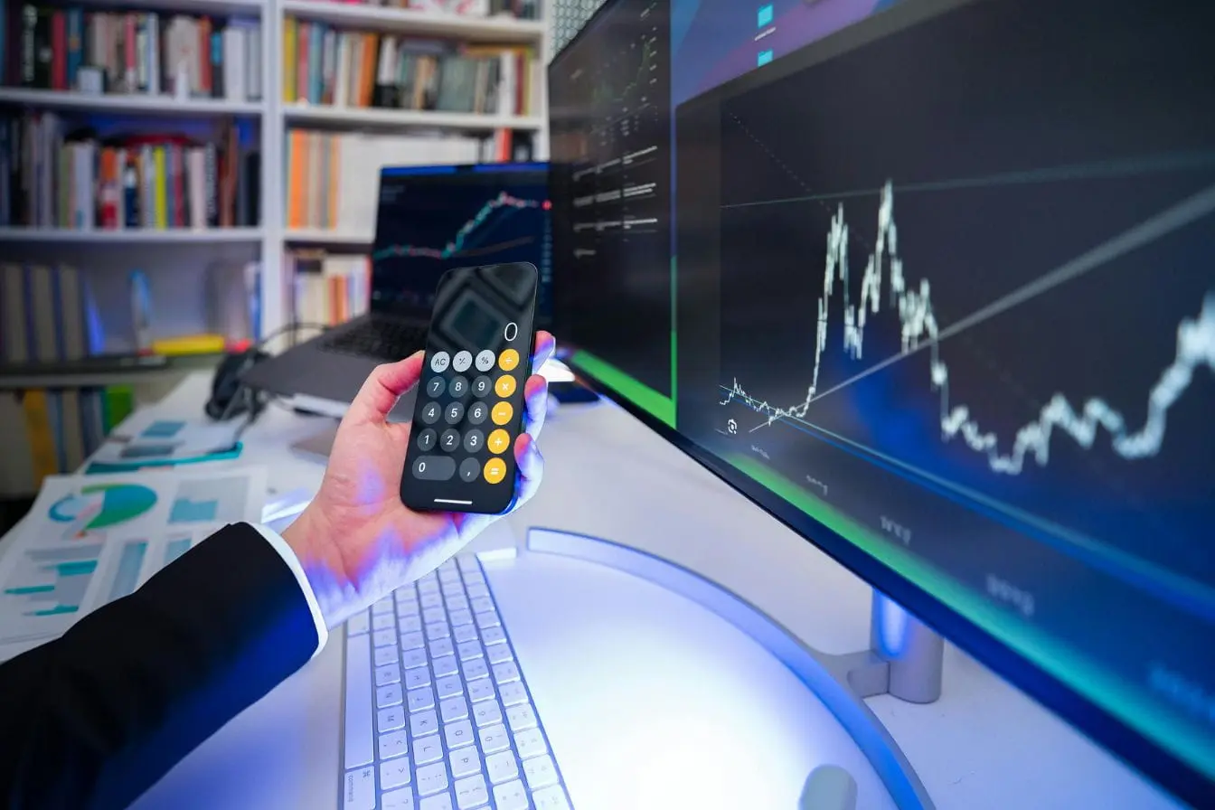 Bureau moderne avec graphiques financiers sur écrans et smartphone, illustrant la rigueur et l’analyse d’une étude de marché.