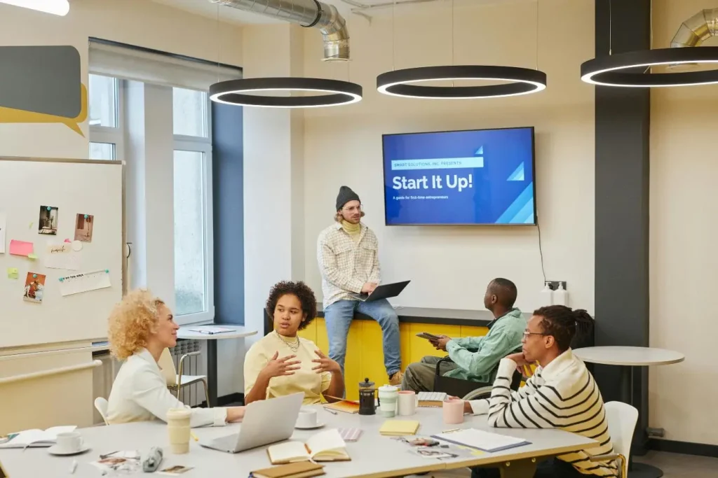 Réunion d’équipe autour d’un écran, image illustrant les différences clés entre incubateur et accélérateur pour accompagner une startup.