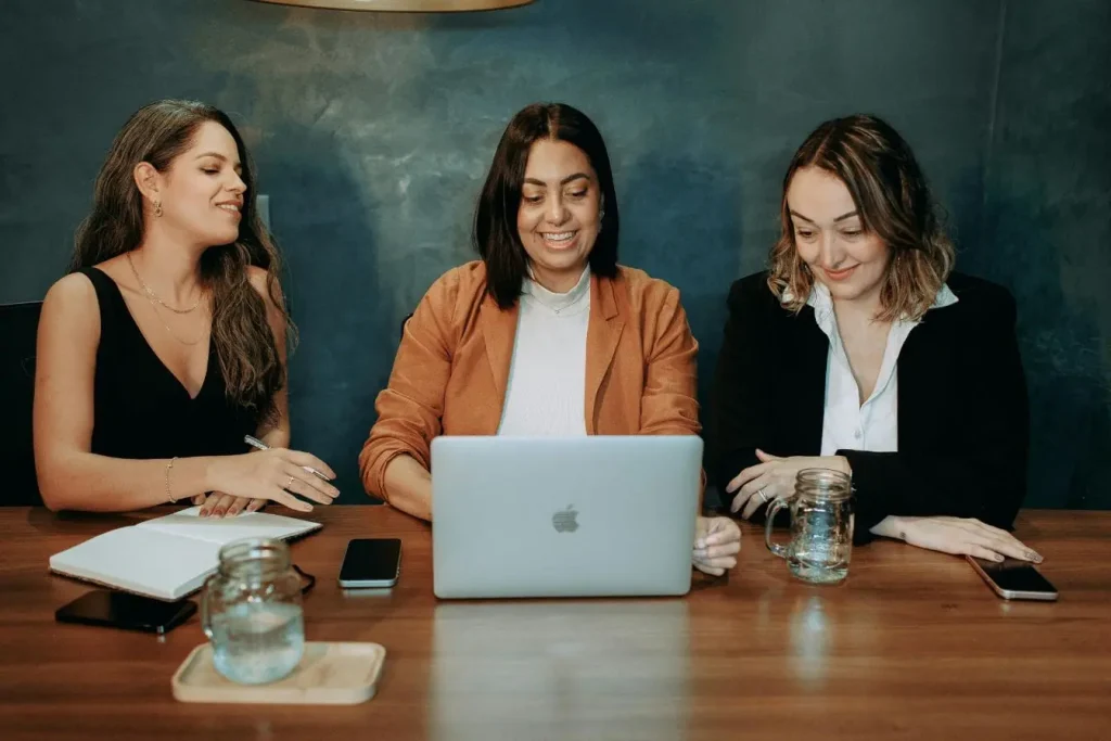 Trois personnes réunies autour d’un laptop argenté, collaborant sur des données partagées grâce au cloud computing dans une ambiance professionnelle.