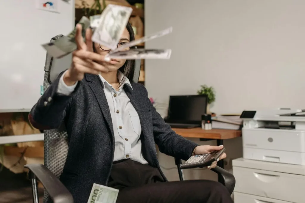 Entrepreneur en costume lançant billets en l’air, image illustrant le lever de fonds pour une startup et la réussite financière.