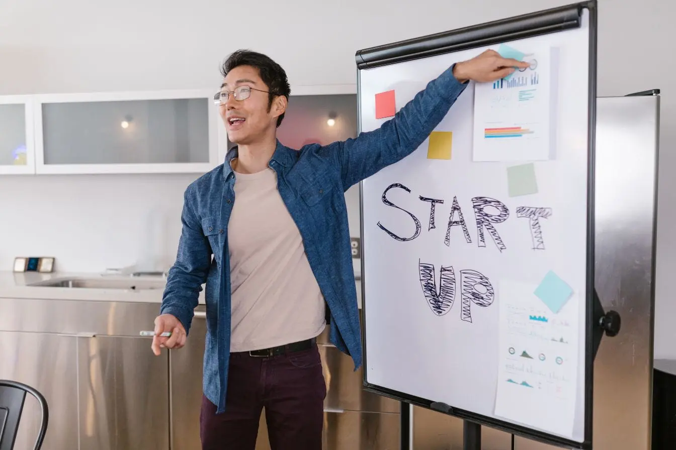 Personne présente devant tableau avec START UP écrit, image illustrant valoriser une startup par stratégie et innovation.
