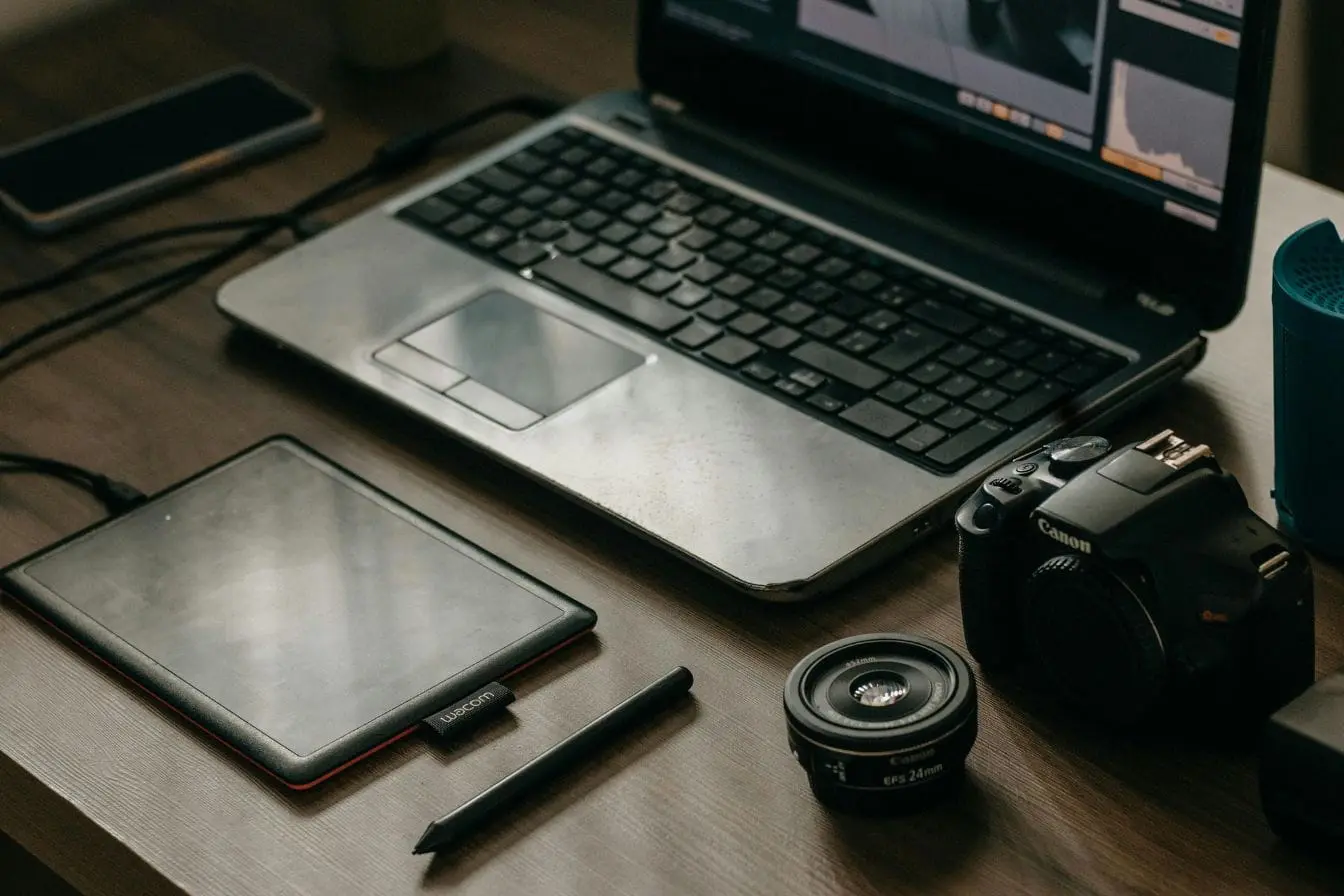 Bureau avec laptop Bureau avec laptop ouvert sur logiciel graphique, image illustrant les outils de gestion de projet pour freelance.