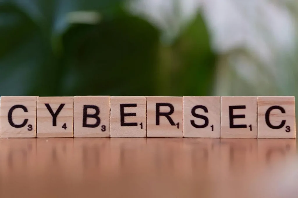 Lettres de Scrabble formant CYBERSEC sur fond vert flou, image représentant la cybersécurité comme stratégie essentielle pour protéger les PME.