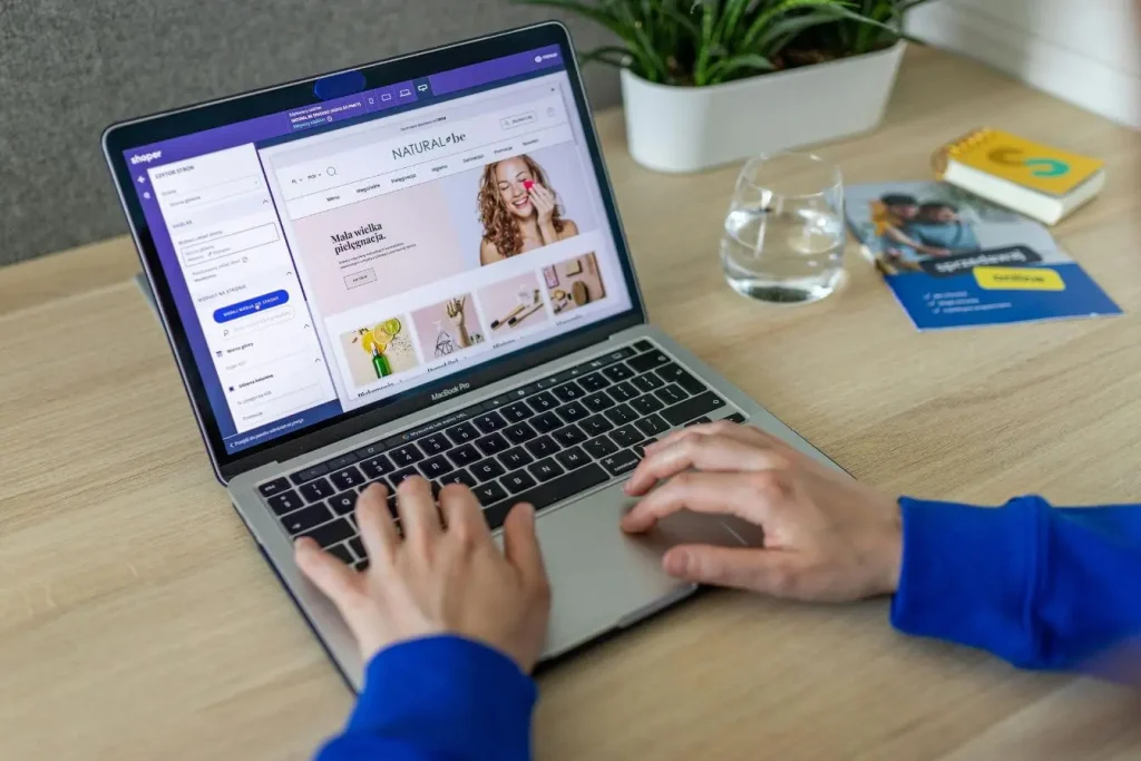 Personne travaillant sur MacBook affichant éditeur de site, image représentant l'utilsation de Threads pour son business et développer une présence digitale.