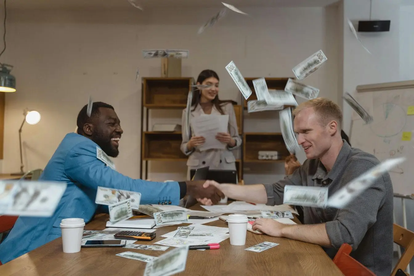 Trois personnes en réunion avec billets flottants, image illustrant la comparaison entre portage salarial et freelance pour sécuriser revenus.