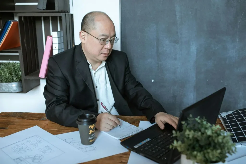 Documents de conception étalés près d’un ordinateur, reflet des critères essentiels du Product Owner.