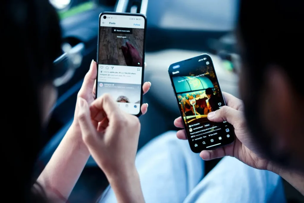 Deux personnes tenant smartphones affichant Instagram Reels, image illustrant l’usage des YouTube Shorts pour renforcer la stratégie digitale des marques.