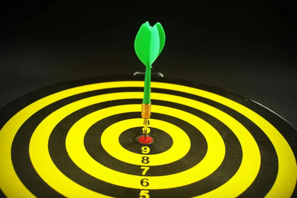 Cible rouge atteinte par une fléchette verte illustrant la précision et l’alignement des objectifs mesurables de la méthode OKR.
