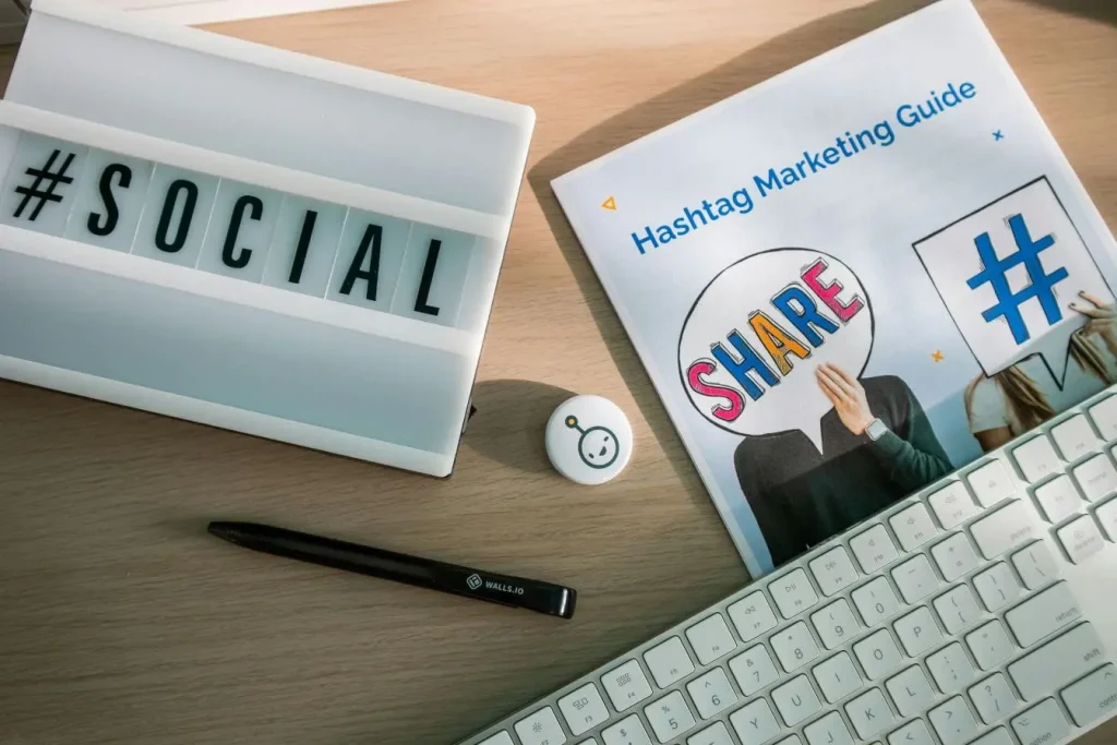 Bureau avec guide marketing hashtag et clavier blanc, image illustrant la différence entre Reach et Impressions en communication digitale.