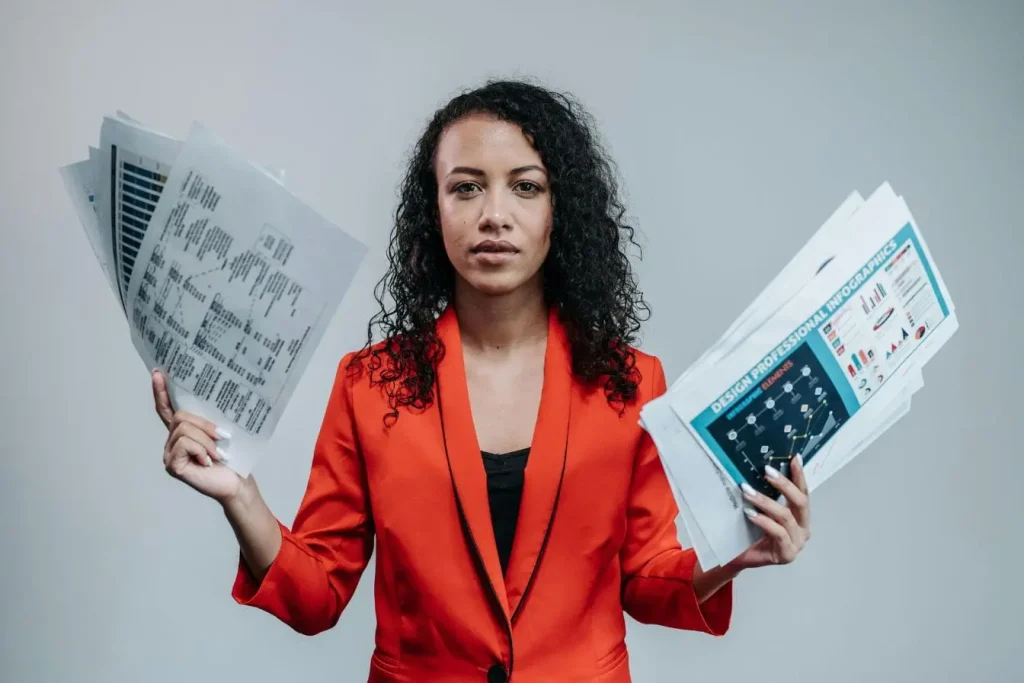 Personne en veste rouge tenant graphiques colorés et tableaux, image illustrant la comparaison entre portage salarial et freelance pour gérer activité.