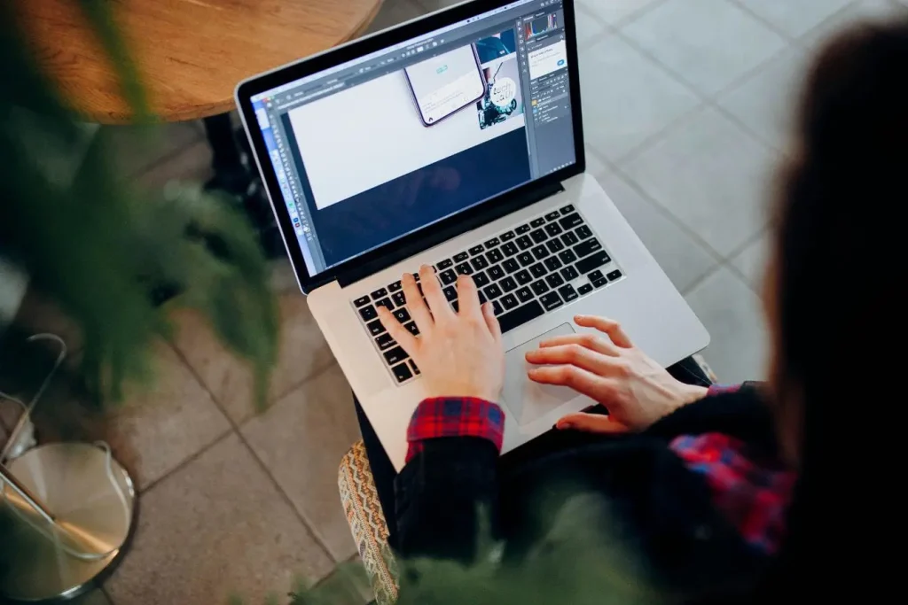Personne travaillant sur laptop avec logiciel de design ouvert, image illustrant l’usage d’outils de gestion de projet pour freelance.