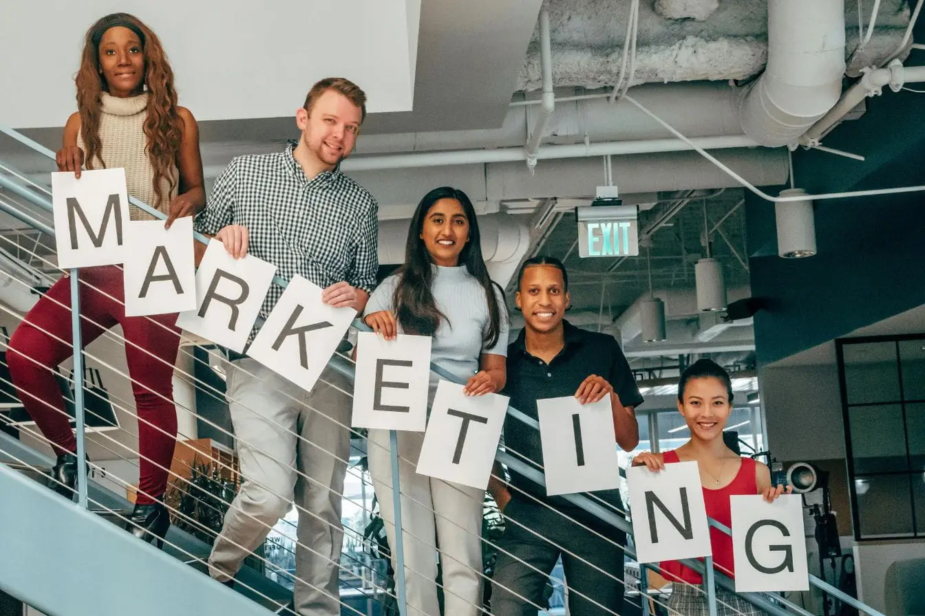marketing Groupe de personnes tenant lettres formant marketing reflétant la distinction entre stratégie commerciale et communication relationnelle.