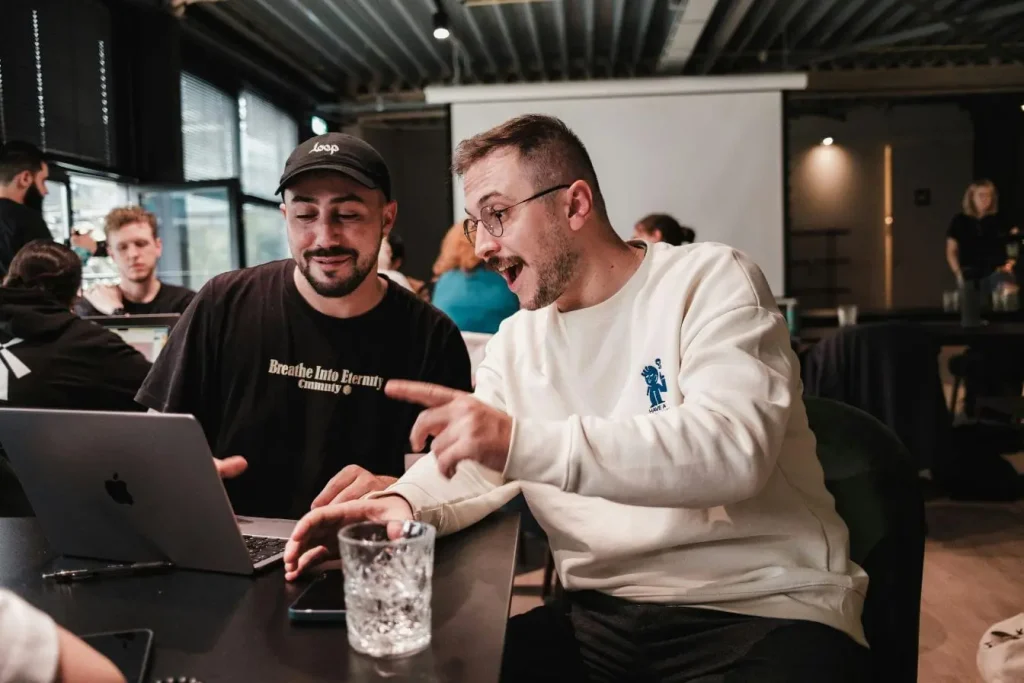 Deux personnes assises devant ordinateur portable discutant projet, image illustrant le pivot en startup lors d’une séance collaborative.