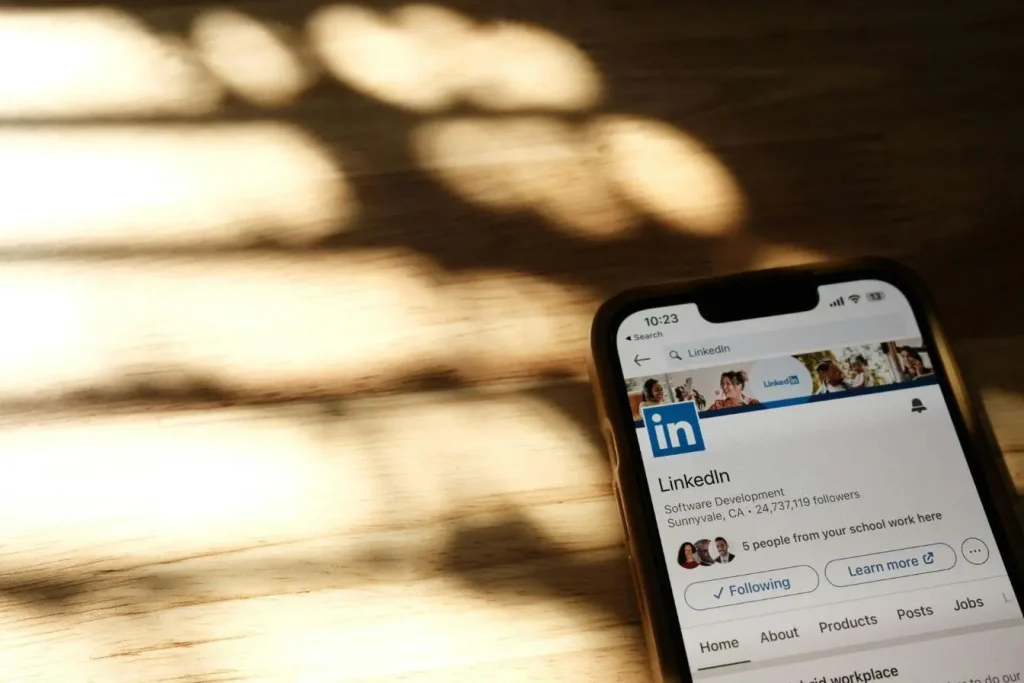 Smartphone posé sur bois affichant profil LinkedIn, illustrant la visibilité réduite causée par le shadow ban sur les réseaux sociaux.