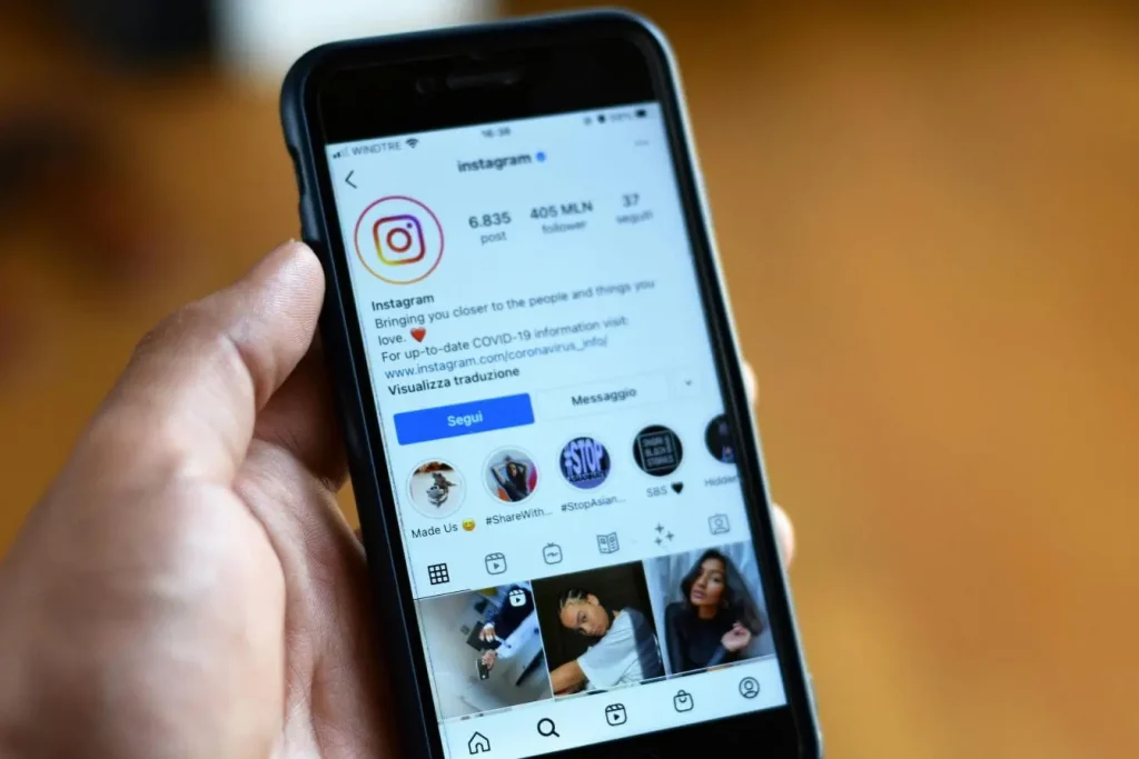 Main tenant un smartphone affichant le profil officiel Instagram, illustrant la puissance du User Generated Content et l’engagement des utilisateurs.