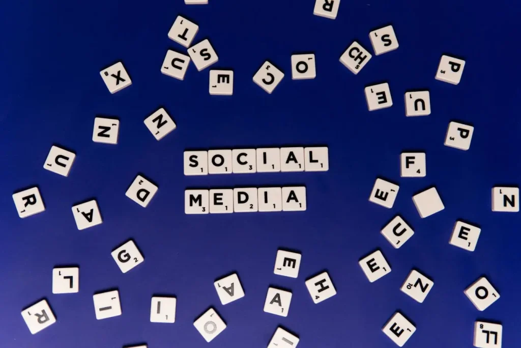 Lettres blanches formant mots social media sur fond bleu, image illustrant la différence entre Reach et Impressions.