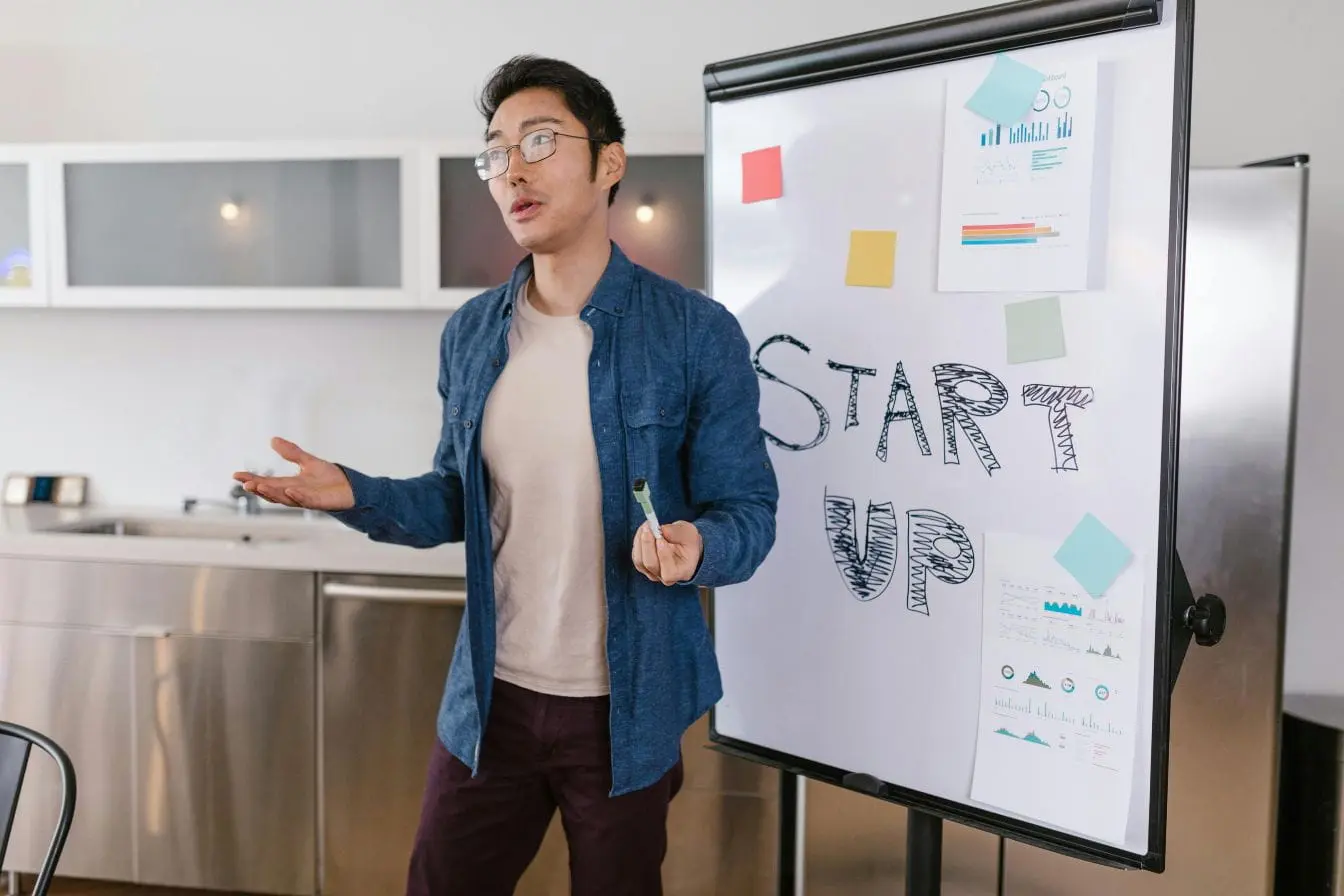 startup Personne debout devant tableau blanc avec mot START UP écrit, image illustrant le pivot en startup lors d’une séance de réflexion stratégique.