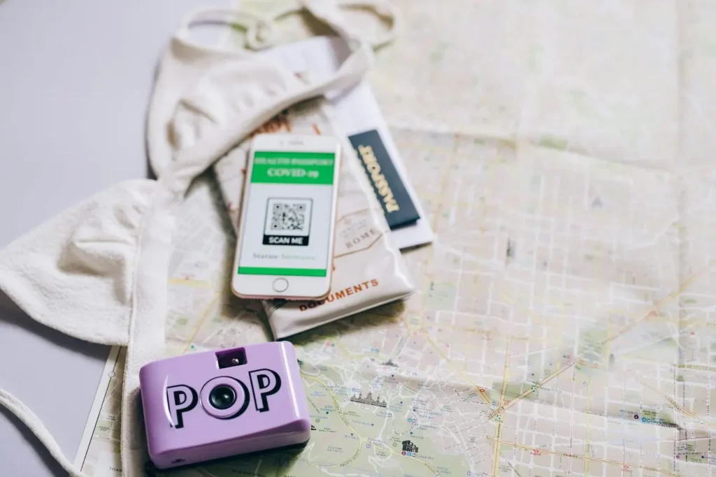 Accessoires de voyage posés sur carte avec passeport et smartphone affichant certificat, illustrant la créativité du User Generated Content.