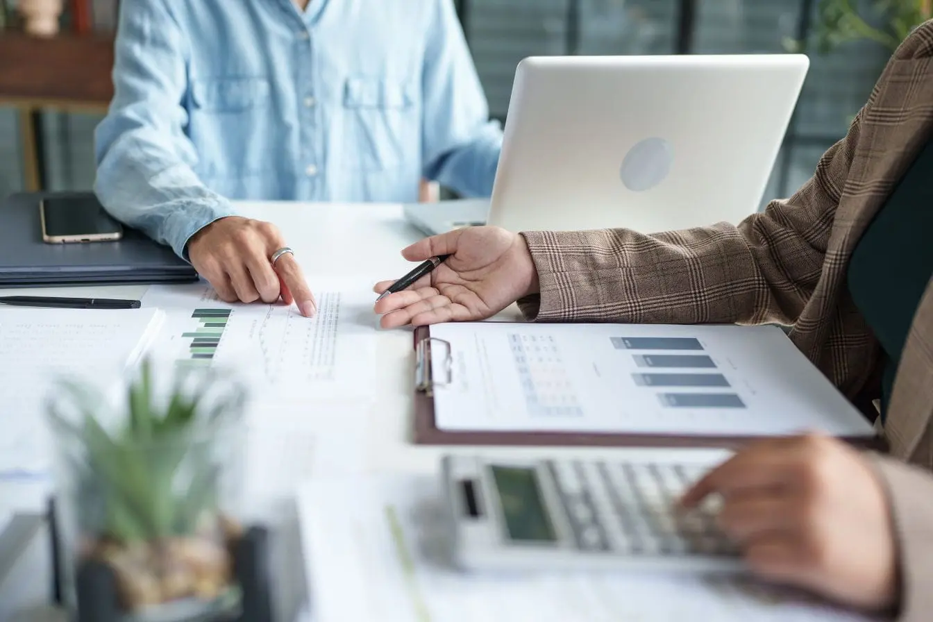 Deux personnes discutent autour de graphiques et d’un ordinateur, image qui illustre la recherche du Product-Market Fit.