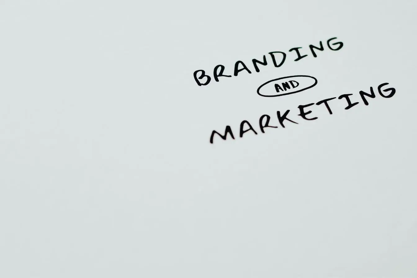 branding et marketing Texte manuscrit branding and marketing sur fond blanc, image qui illustre la distinction entre identité de marque et actions de promotion.