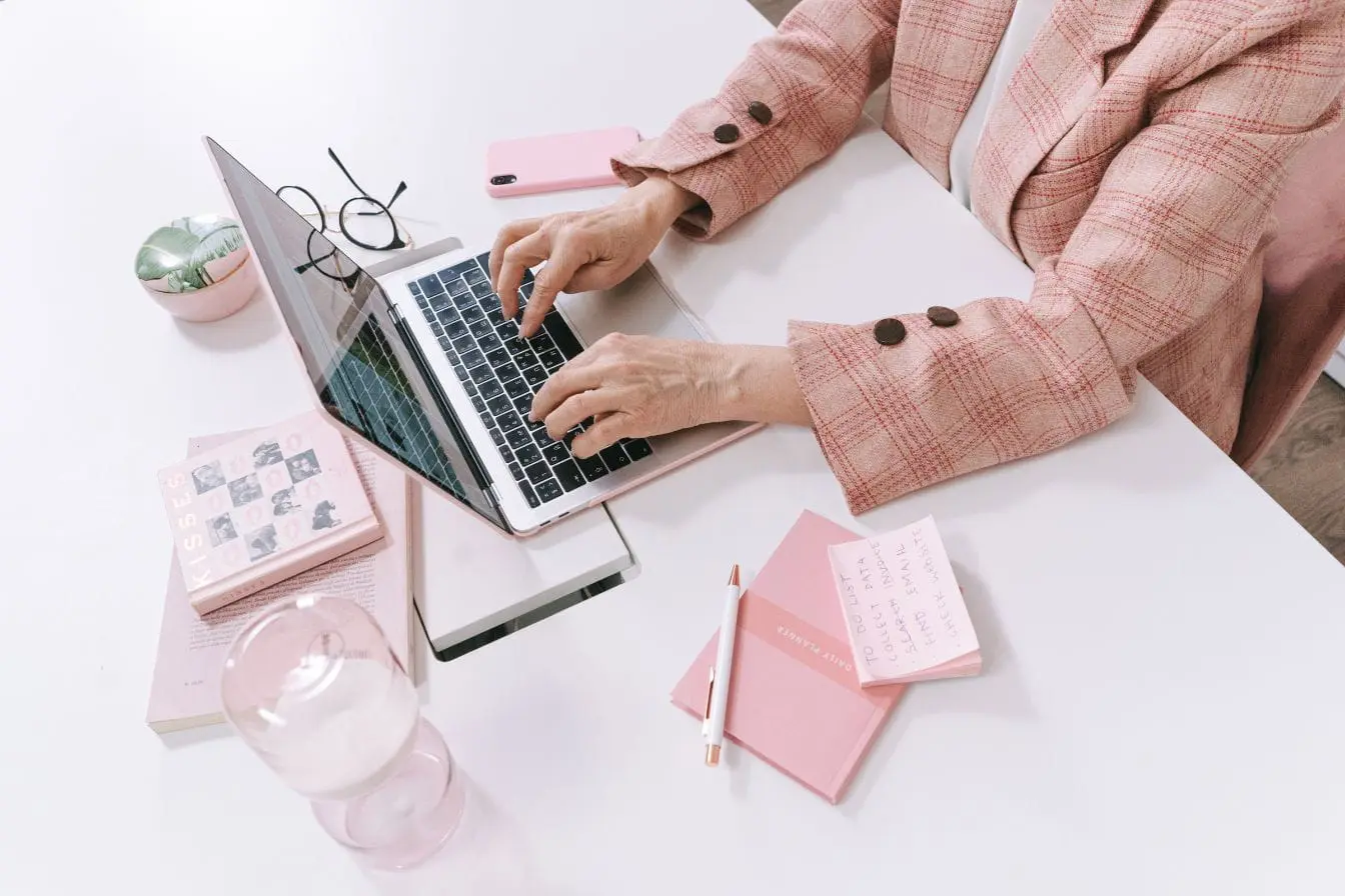 cold emailing Personne en veste rose tape sur ordinateur portable, image illustrant la préparation d’un cold emailing organisé et ciblé.