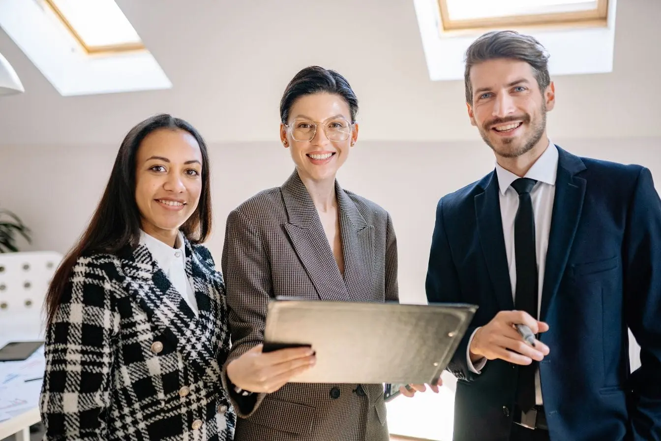 Trois personnes en tenue professionnelle discutant dans bureau lumineux, image qui illustre la force de l’employer branding dans un cadre collaboratif.