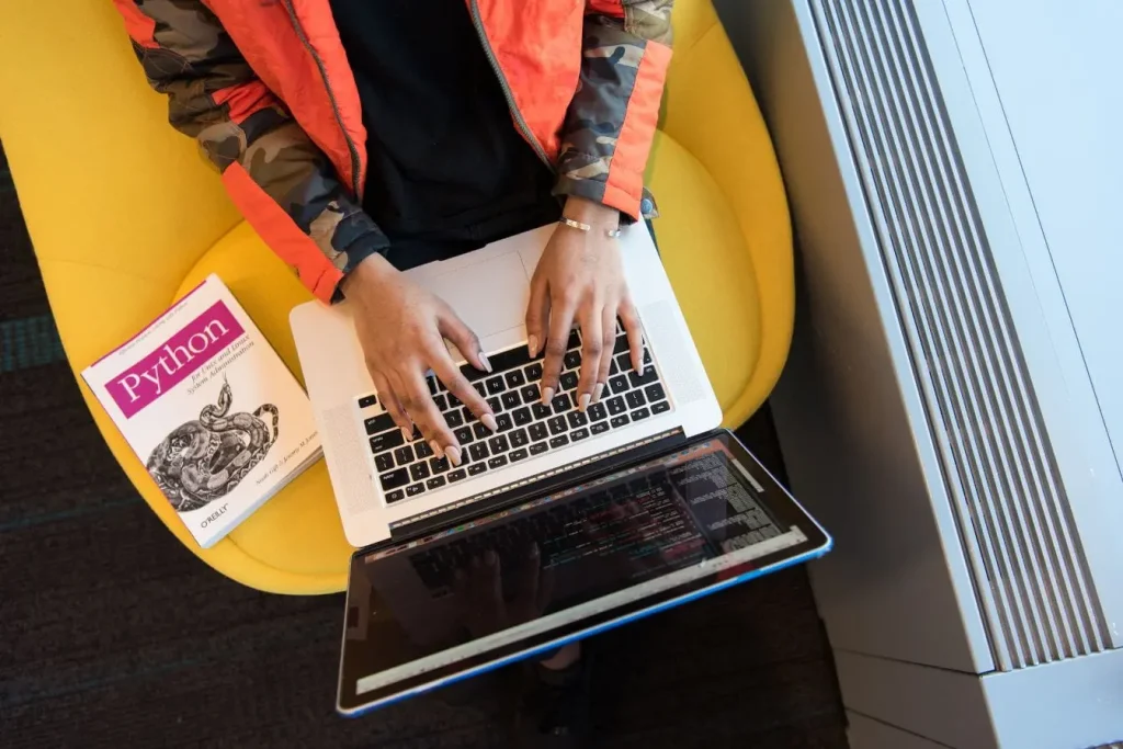 Personne tape sur ordinateur portable affichant code Python, image illustrant le développement d’applications serverless.
