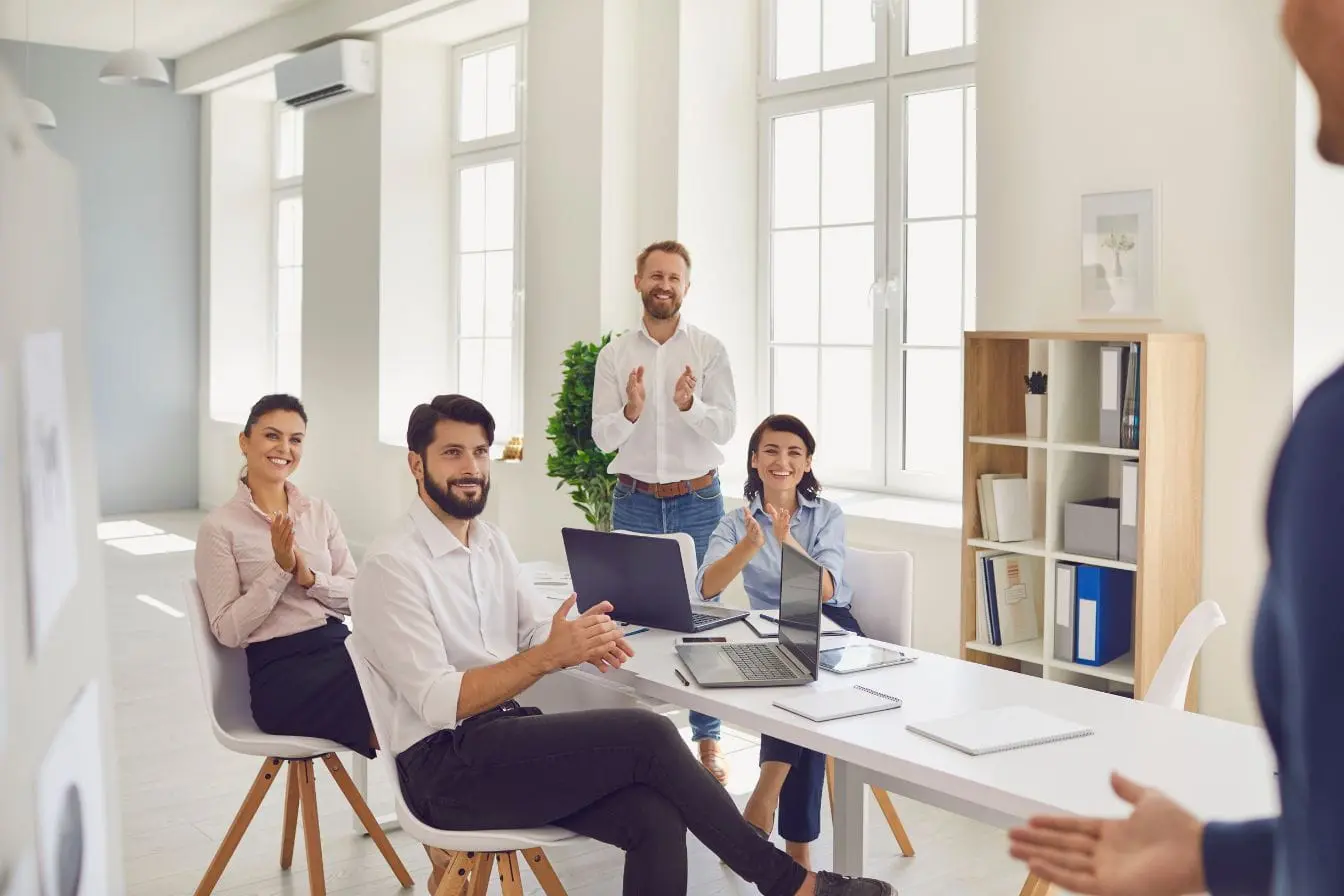 mise en place du RGPD pour les entreprises Groupe en réunion applaudit autour d’une table blanche, image illustrant la mise en place du RGPD pour les entreprises.
