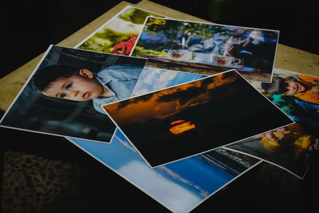 Collection de photos imprimées en print on demand, portraits et paysages personnalisés étalés sur surface pour sélection artistique.