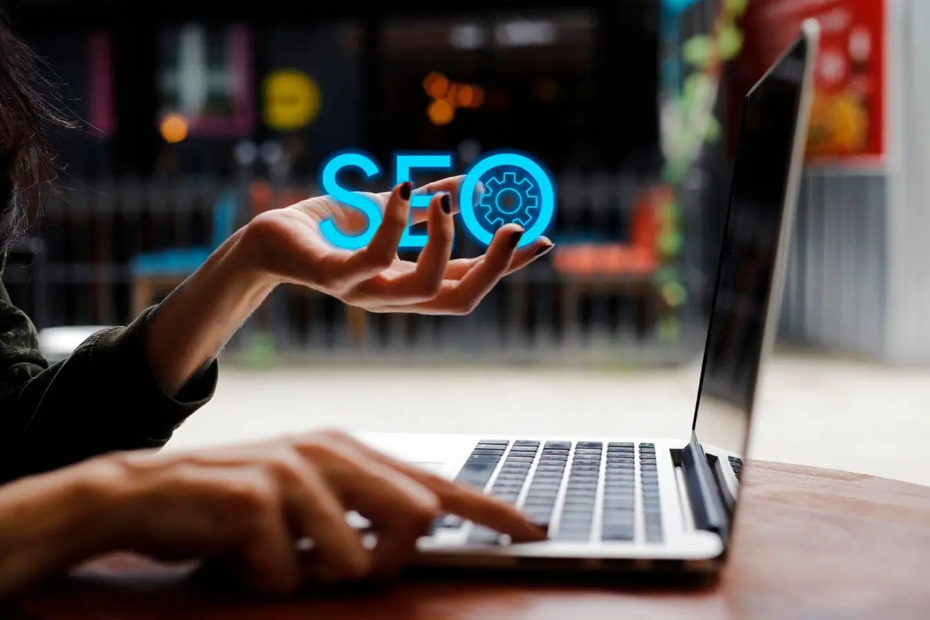 SEO Main tenant texte lumineux SEO au-dessus clavier, reflet des enjeux du duplicate content dans l’optimisation.