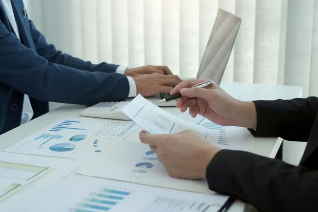 Deux personnes assises à un bureau analysant graphiques et données, image qui illustre un moment clé d’onboarding client.