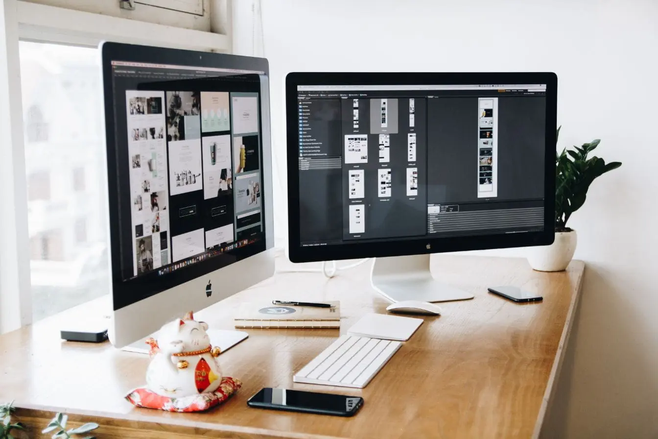 Bureau moderne avec deux écrans affichant des maquettes, image qui illustre la mise en place d’un Design System