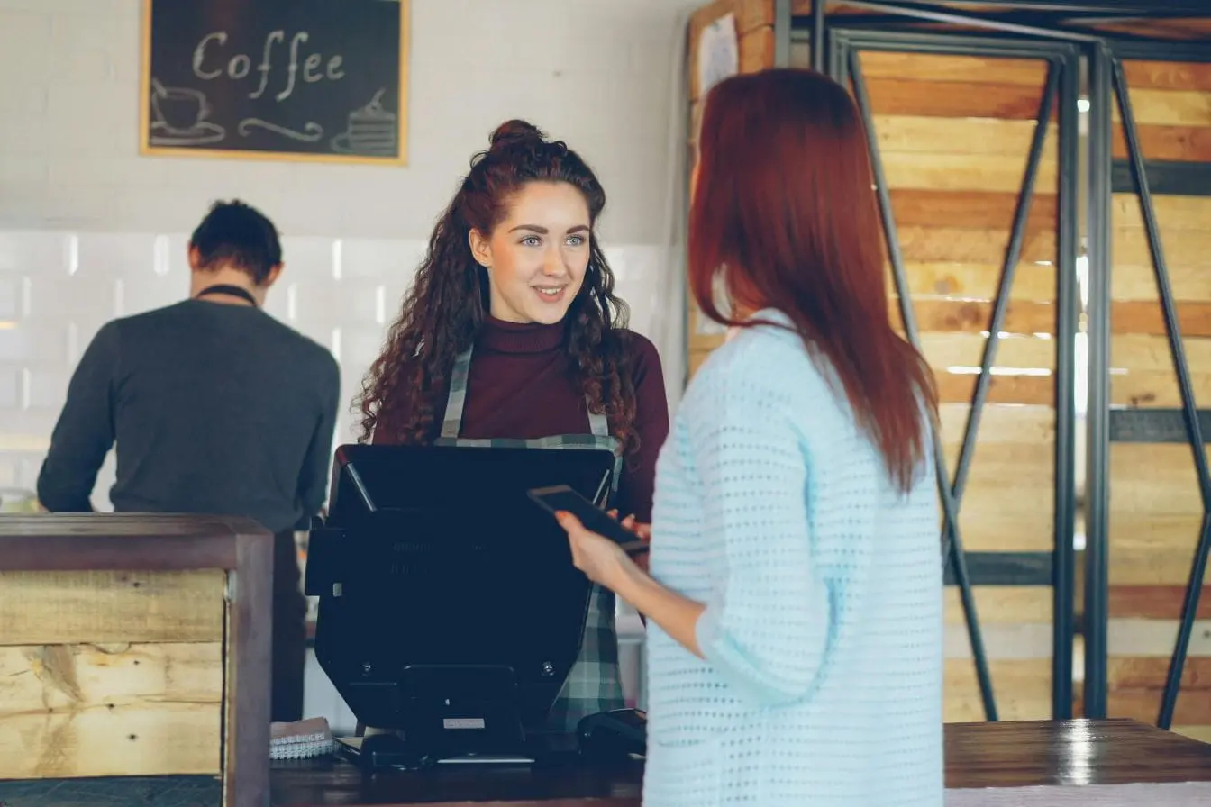 Client discutant avec barista derrière comptoir de café, image qui illustre une étape clé du customer journey.