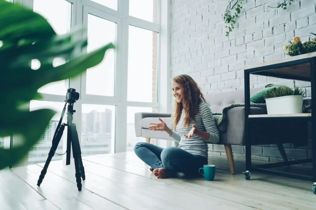 Personne assise au sol devant caméra sur trépied, sourire naturel et gestes dynamiques, reflet d’une création de snack content engageant.