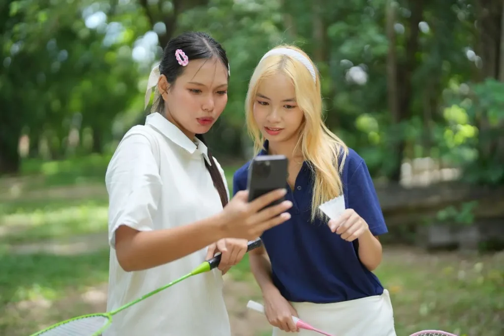 Amis dans un parc concentrés sur écran de téléphone, reflet du rôle du social proof dans les décisions collectives.