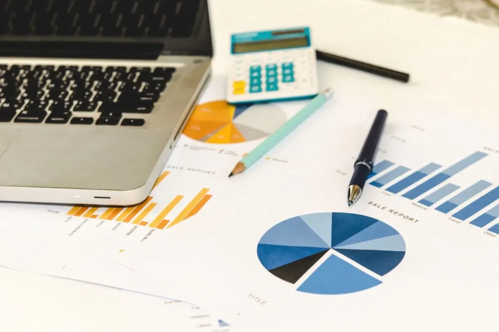 Bureau avec ordinateur portable, calculatrice et graphiques colorés, image qui illustre l’analyse de données pour une stratégie Account Based Marketing.