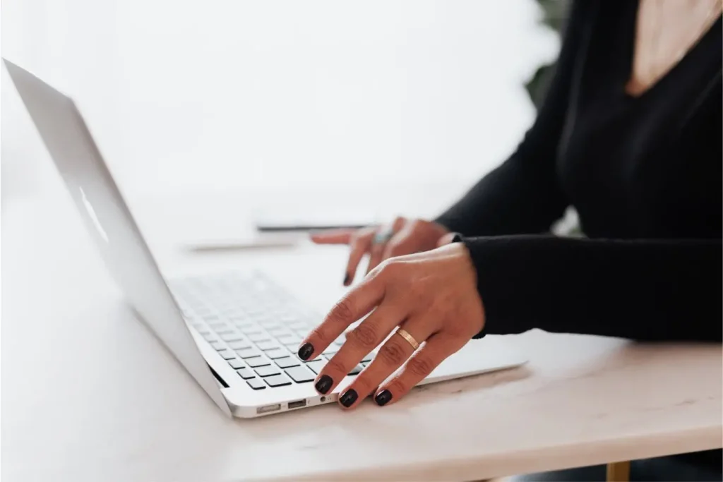 Gros plan sur mains tapant sur clavier d’ordinateur portable, image qui illustre la construction d’un topic cluster en SEO.