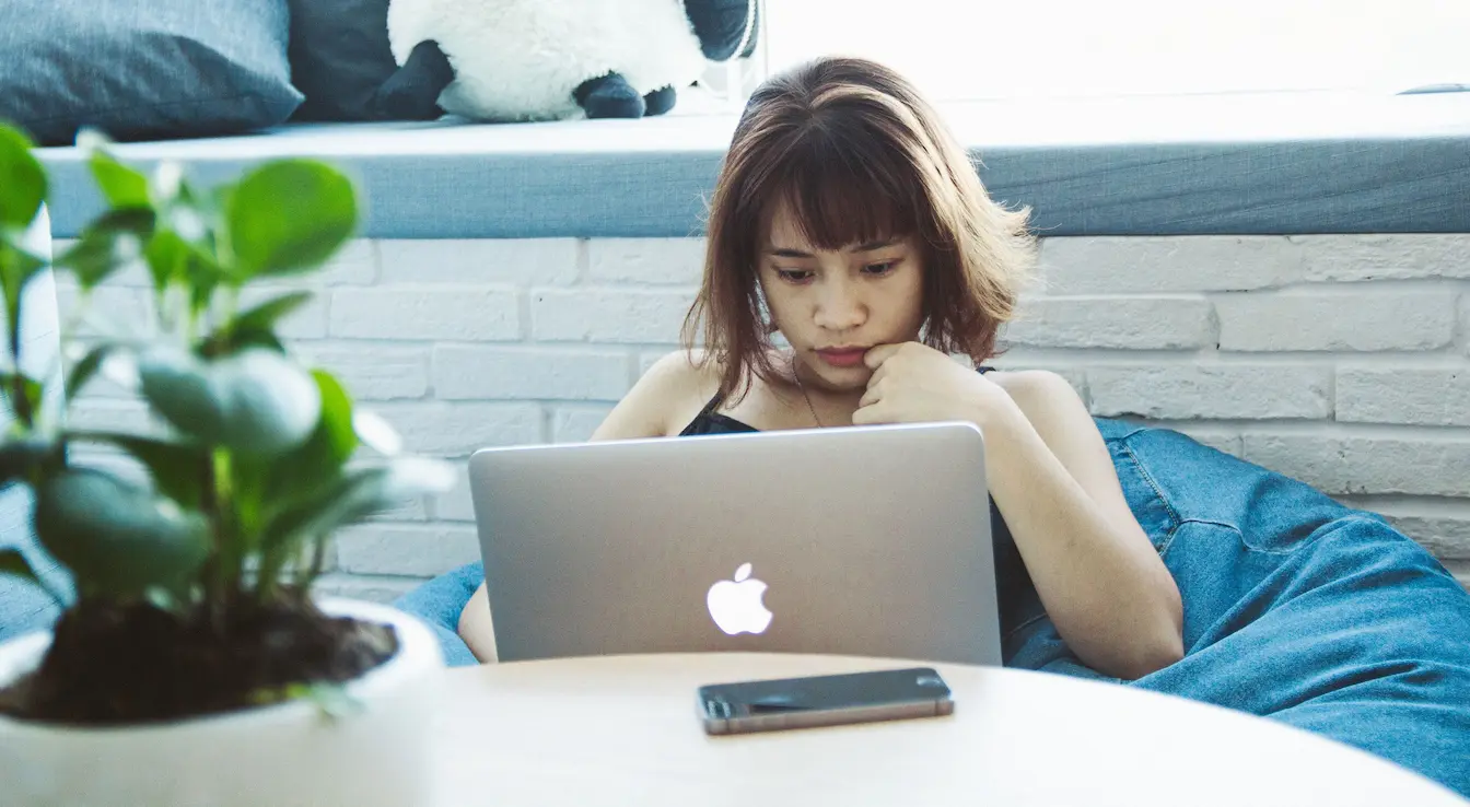 Freelance vs Salarié Gros plan sur MacBook argenté posé sur table bois, image claire illustrant le comparatif Freelance vs Salarié.