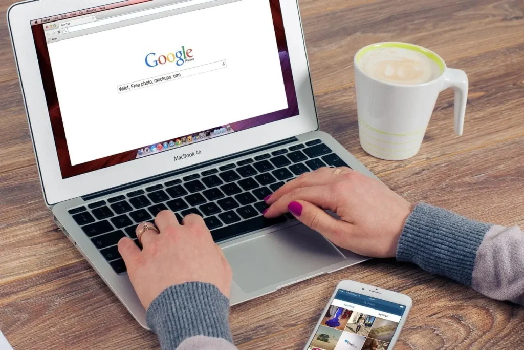 Personne tapant sur MacBook Air affichant recherche Google, reflet des critères EAT pour expertise et fiabilité du contenu.
