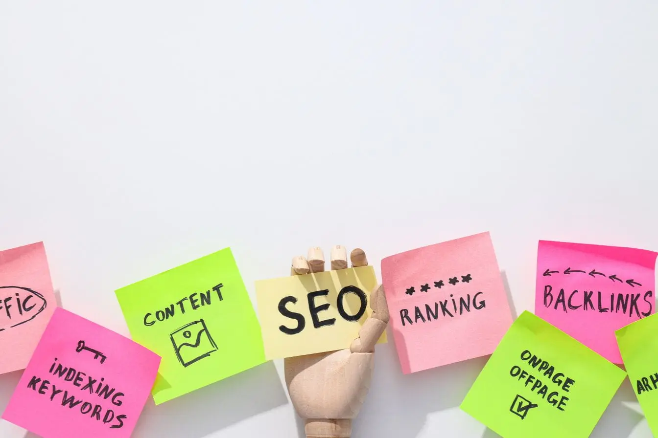 Post‑it SEO Main tenant post‑it jaune marqué SEO entouré de notes colorées, reflet d’une cannibalisation SEO où plusieurs contenus ciblent les mêmes mots‑clés.