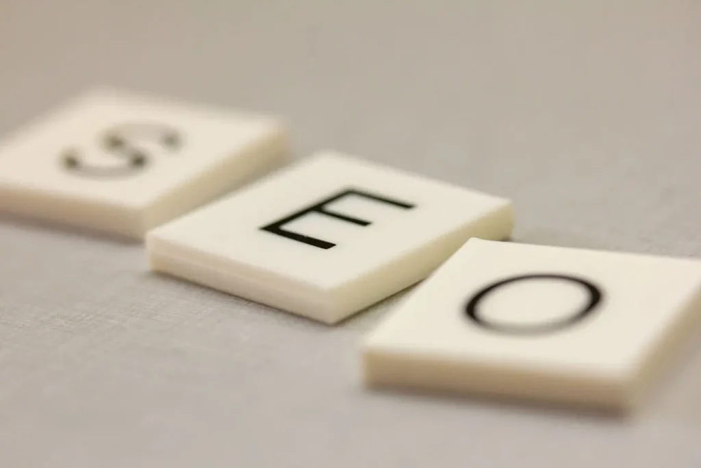 Trois carreaux blancs alignés formant SEO, reflet des choix stratégiques entre longue traîne et mots-clés génériques en 2026.